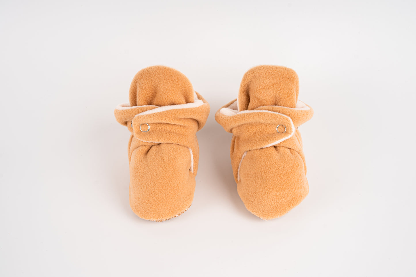 Comfortable and breathable baby booties in camel with non-slip soles for safe adventures. Front view.