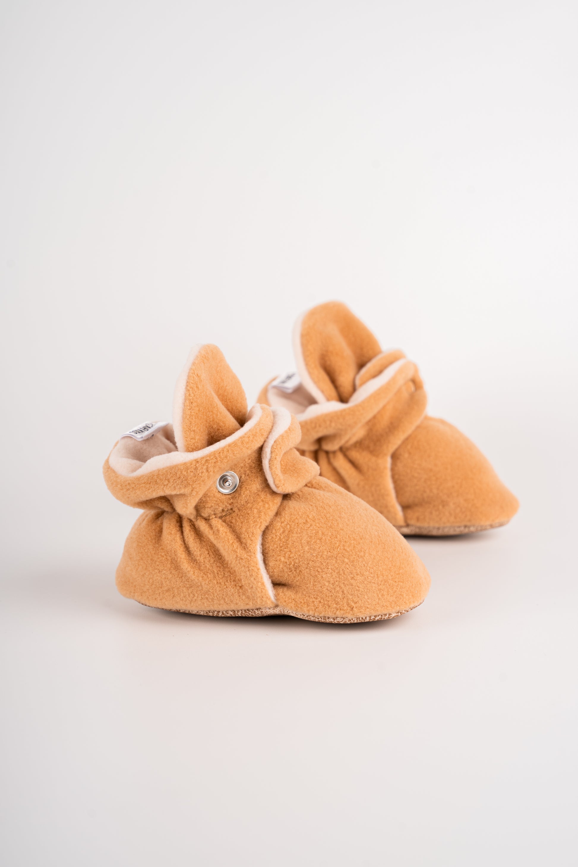 Comfortable and breathable baby booties in camel with non-slip soles for safe adventures. Left double view.